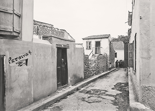 Black and white photo of Ptolemaiou Street in September 1932. There is a group of women standing at the far end of the street near the Church of Vlassarou